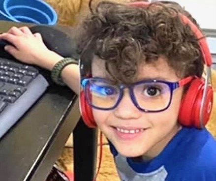 young boy in glasses looking up from computer